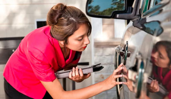 An adjuster writing up damage beside the vehicle