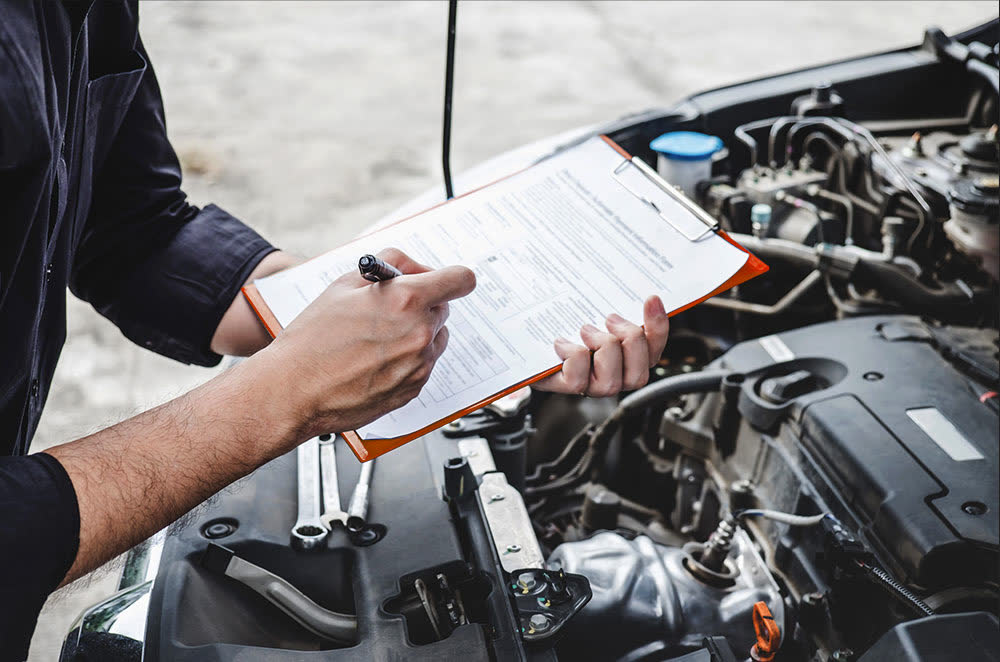 An inspection checklist on a clipboard beside an open engine bay