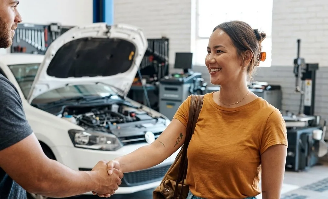 A customer shaking hands with a mechanic in the shop