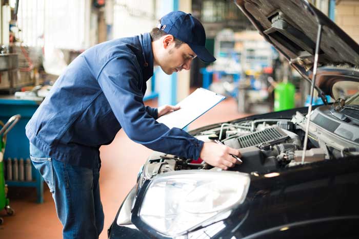 An inspector working through an engine bay with a clipboard